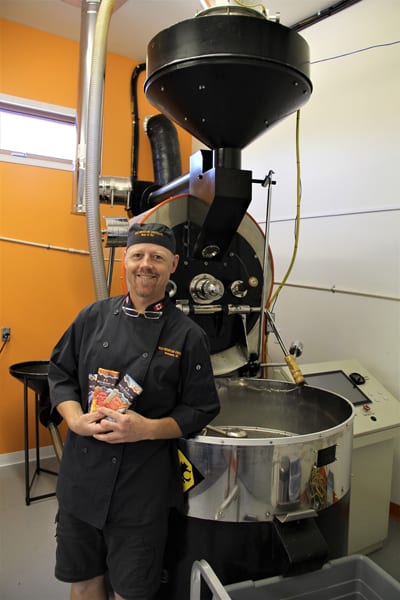 Wild Mountain Chocolate founder and owner Glen Davies, pictured with the roaster he purchased from Kicking Horse Coffee and his three current varieties of origin chocolate, opened his business in Invermere in late June and is already hiring more staff to keep up with the orders pouring in. Photo by Nicole Trigg 